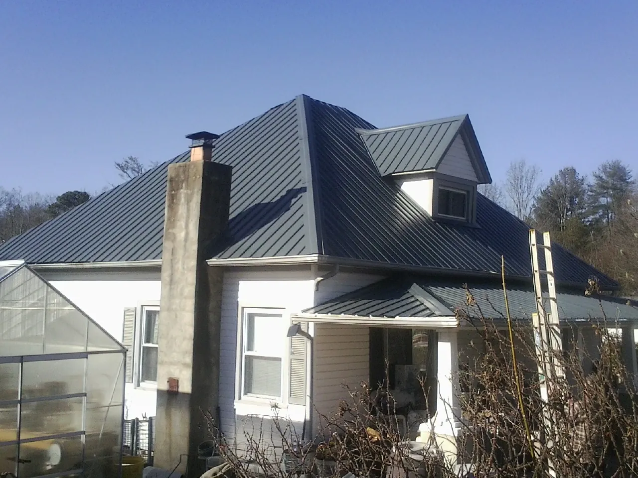 Dark blue standing seam metal roof on a white farmhouse with dormer — Slate & Tile Roof Repair by Roofing Brothers in Olympia