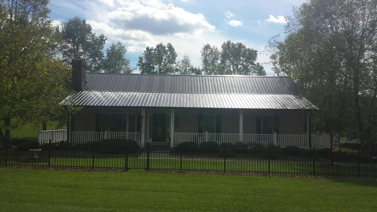Gray metal roof on a brick ranch with a full width front porch — Gutter Guard Installation work by our crew in Olympia
