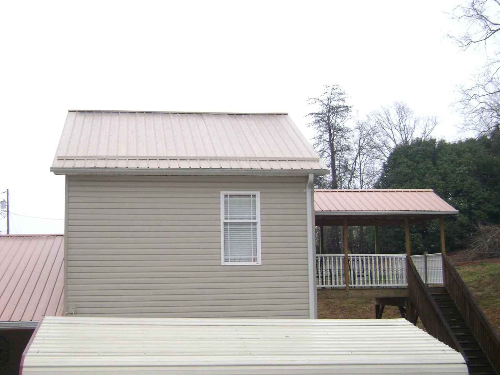 Tan metal roofs on a two story addition and attached porch, from a Roof Replacement job in Olympia