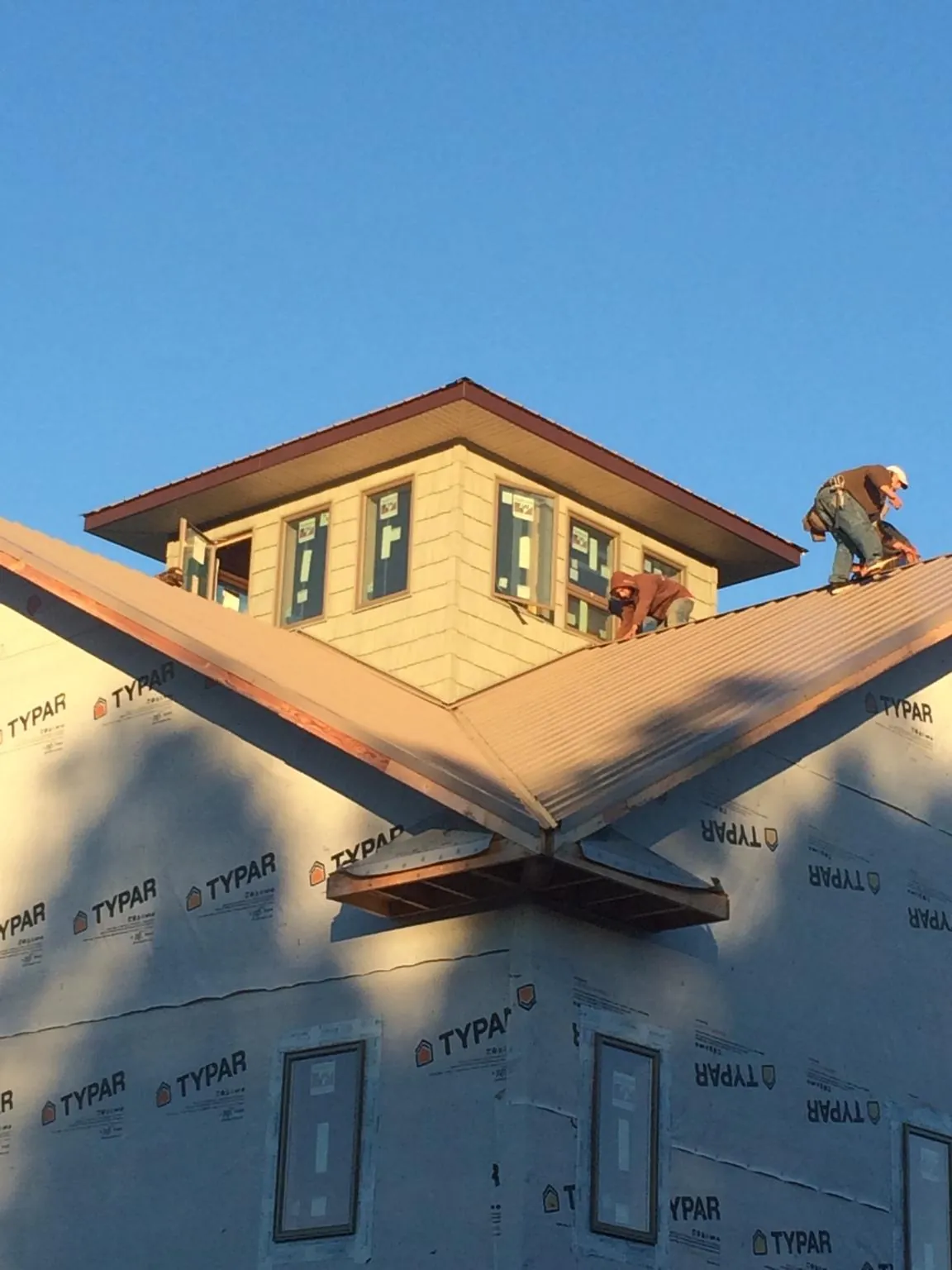 Roofers working around a rooftop cupola on a new metal roof at sunset — Roof Waterproofing in Olympia by Roofing Brothers